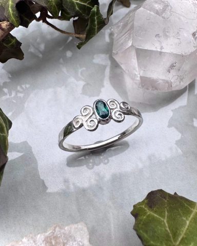 Silberner Ring mit blauer Edelsteineinfassung und verschnörkeltem Design.