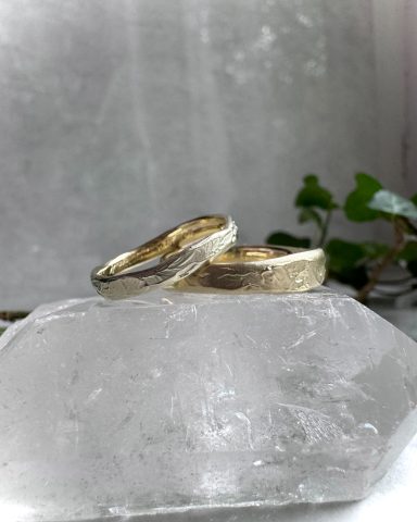 Zwei goldene Ringe auf einem klaren, glatten Stein vor einem weich verschwommenen Hintergrund.